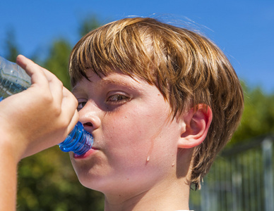 年轻的男孩在喝一瓶水