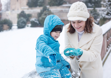 母亲和蹒跚学步的孩子冬天天过与雪的乐趣