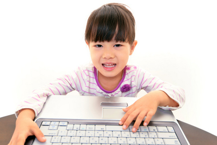 快乐的小亚洲女孩微笑与便携式计算机