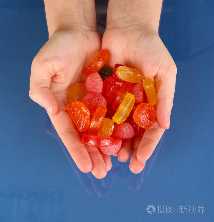 手里的糖果在蓝色背景照片-正版商用图片1b9nks-摄图新视界