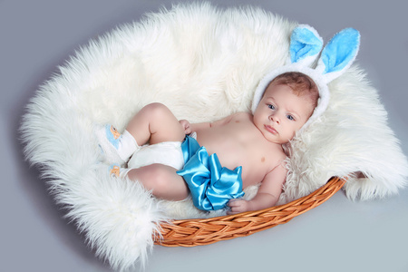 初生婴儿用蓝色弓躺在灰色背景