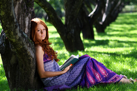 年轻女子在夏天，绿色公园读的书