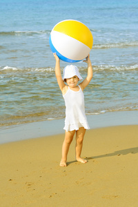 蹒跚学步女孩在海滩上玩她充气球