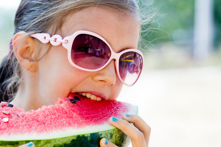 childbeach在十分炎热的夏天吃西瓜的小女孩照片