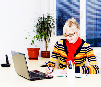 在工作桌前使用便携式计算机的年轻商业女人