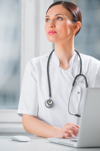 一名女医生在诊所使用她的便携式计算机的肖像