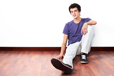 年轻人坐在木地板和空白墙与副本