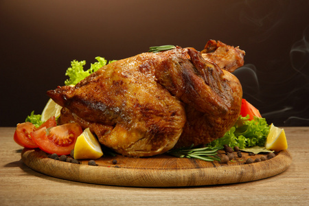 整个烤的鸡配蔬菜 木桌上，棕色背景上
