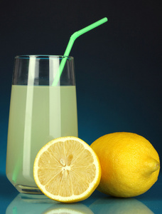 在玻璃和它旁边暗蓝色背景上的柠檬美味柠檬汁