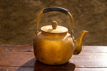 在老式的木桌上古董黄铜茶壶