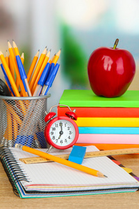 学校用品与苹果和木制桌上的时钟