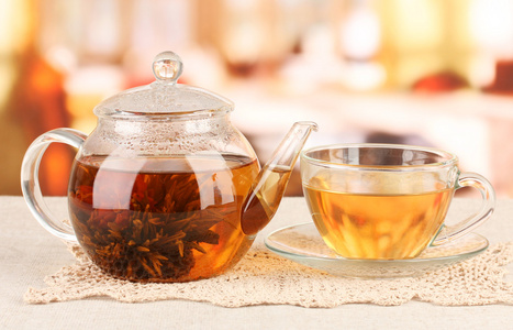 异国情调绿茶与鲜花在明亮的背景上的玻璃茶壶