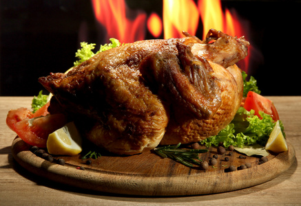 整个烤的鸡配上火焰背景板上的蔬菜