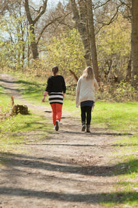 两名妇女行走在春天森林中的路径