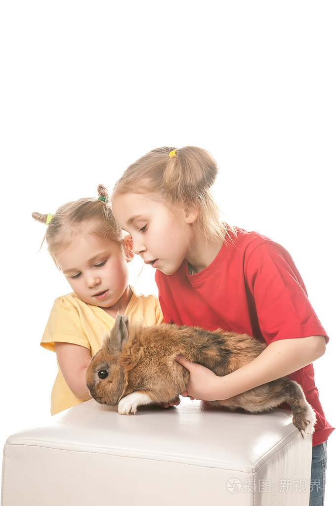 玩复活节兔子在白色背景上的两个小女孩