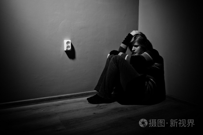 伤心女人独自坐在一个空的房间-黑色和白色
