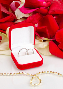 美丽的盒子与孤立在白色的红 白 粉红玫瑰花瓣背景上的结婚戒指