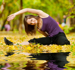 女人在做瑜伽锻炼在秋天的公园