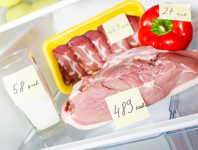 新鲜的肉与标记卡路里冰箱里的近距离视图