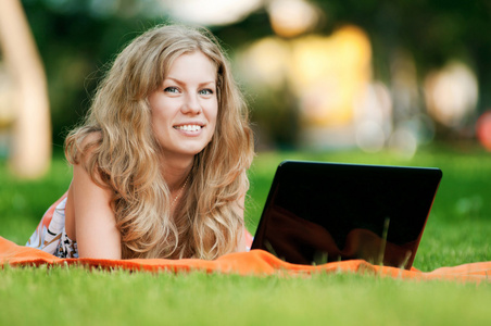 年轻女子在公园的笔记本电脑