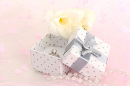 美丽的盒子与结婚戒指和粉红色的背景上的花