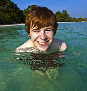 红头发的男孩喜欢水晶般清澈的水在海