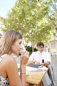 商人和女商人在经典的城市户外使用技术虽然在咖啡厅的露台表