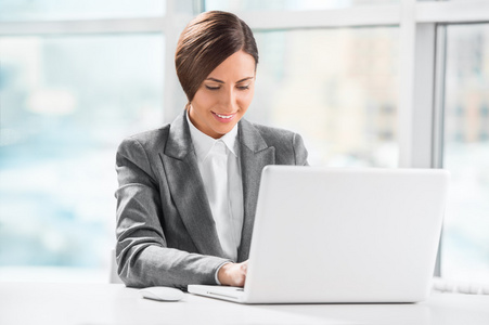 繁忙的白种人商业女人在办公室的桌前使用便携式计算机