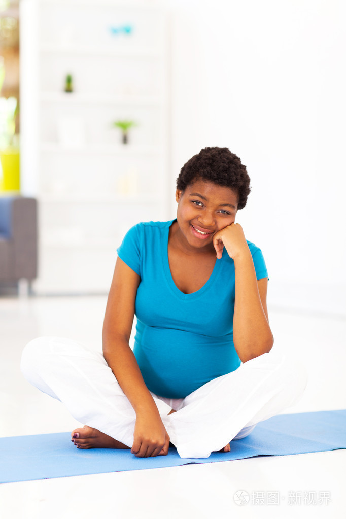 坐在家里练习垫上的非洲裔美国孕妇