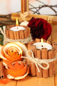 从干橙皮和燃烧蜡烛木桌上的装饰玫瑰