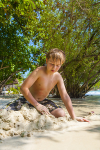 快乐的小男孩挖沙的海滩和建设