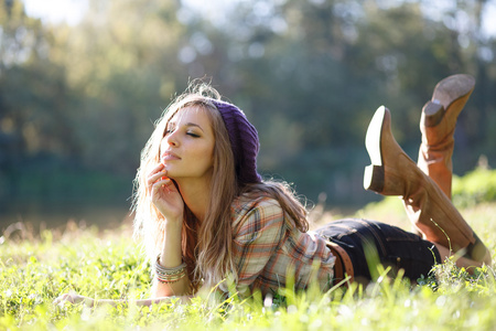 美丽的年轻女子躺在草地上，闭上眼睛