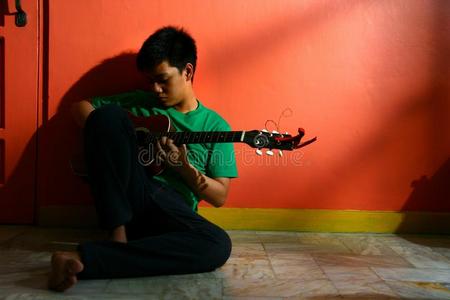 年轻的亚洲青少年在客厅弹吉他
