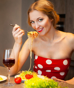 一个金发女人在家里的厨房里吃意大利面