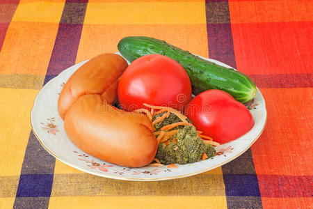 两个大香肠和蔬菜放在一个白色的盘子里。