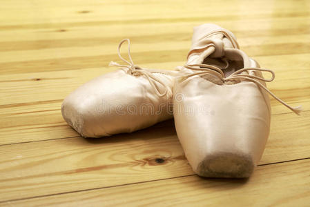 一双芭蕾舞鞋指向木地板