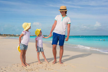 可爱的小女孩和快乐的父亲在热带白色沙滩上