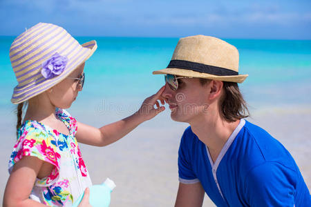 小女孩涂着爸爸鼻子上的防晒霜