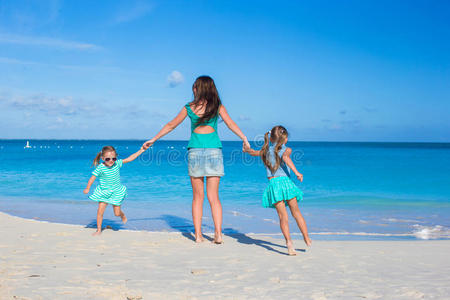 快乐的妈妈和她可爱的女孩们在热带海滩玩得开心