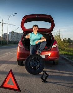 男人坐在汽车后备箱上,脚放在备胎上照片