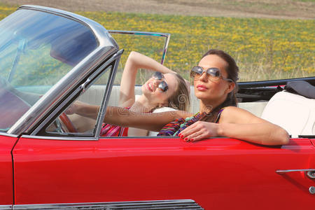 戴着太阳眼镜的美女坐在一辆老式汽车里照片