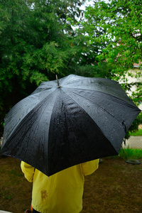 五彩缤纷的阳伞和雨滴下雨时,男人在黑伞下照片