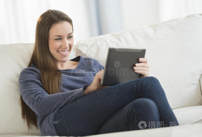 在沙发上使用数字平板电脑的女人