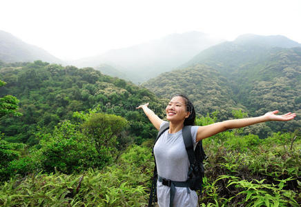 女徒步旅行者在日出山顶张开双臂