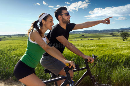 一对快乐的年轻夫妇在乡下骑自行车