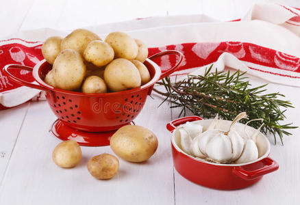新鲜有机土豆，迷迭香和大蒜在白木棒上
