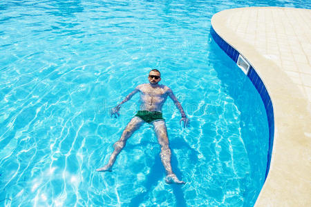 阳光明媚的日子里，男人在游泳池里游泳