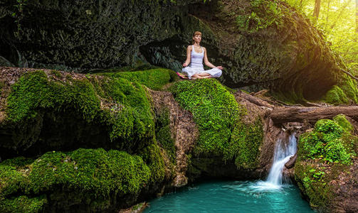 女人在自然瀑布练习瑜伽。苏哈萨纳式