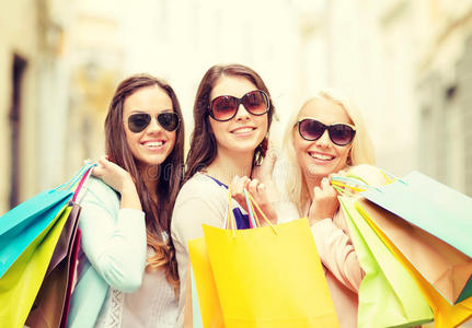 三个微笑的女孩拿着购物袋进城