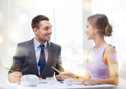 微笑的情侣在餐厅吃寿司
